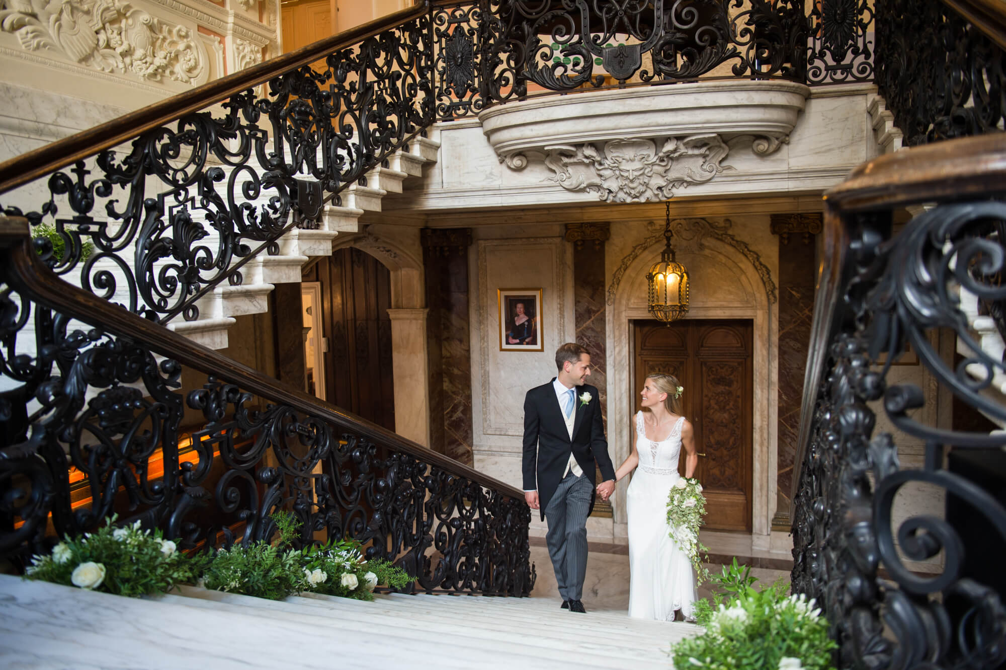 A newly married couple walking up the marble staircase of Dartmouth House in London